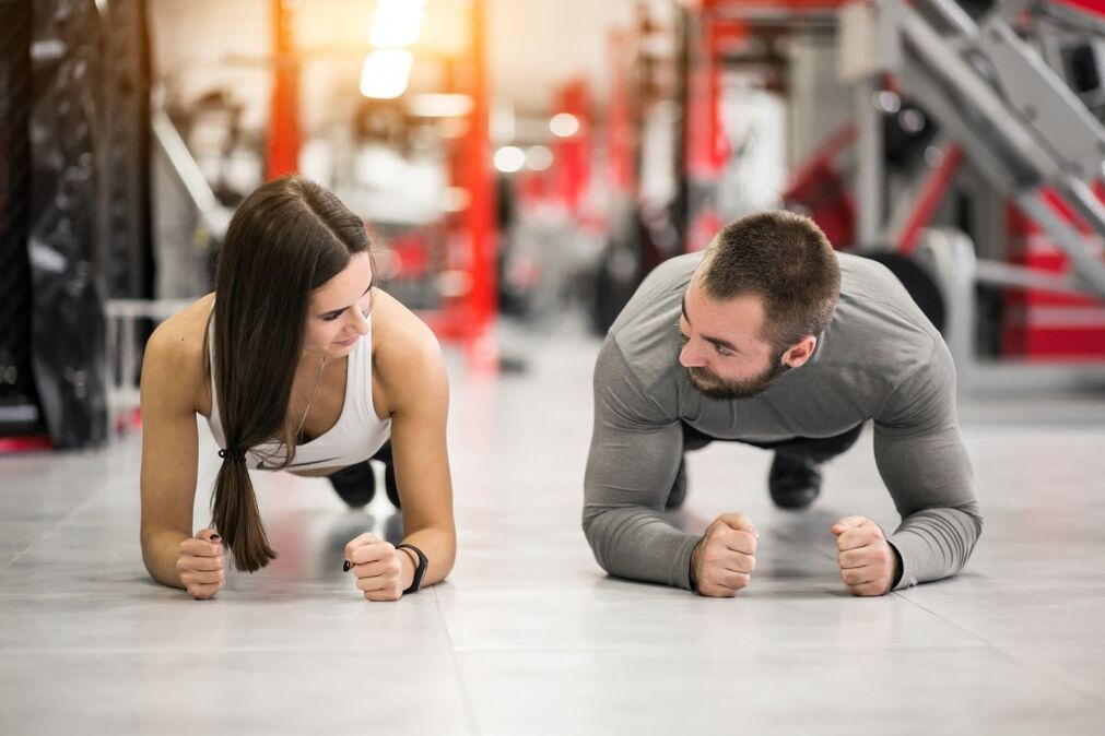 Um homem e uma mulher realizam o exercício Plank, projetado para todos os grupos musculares